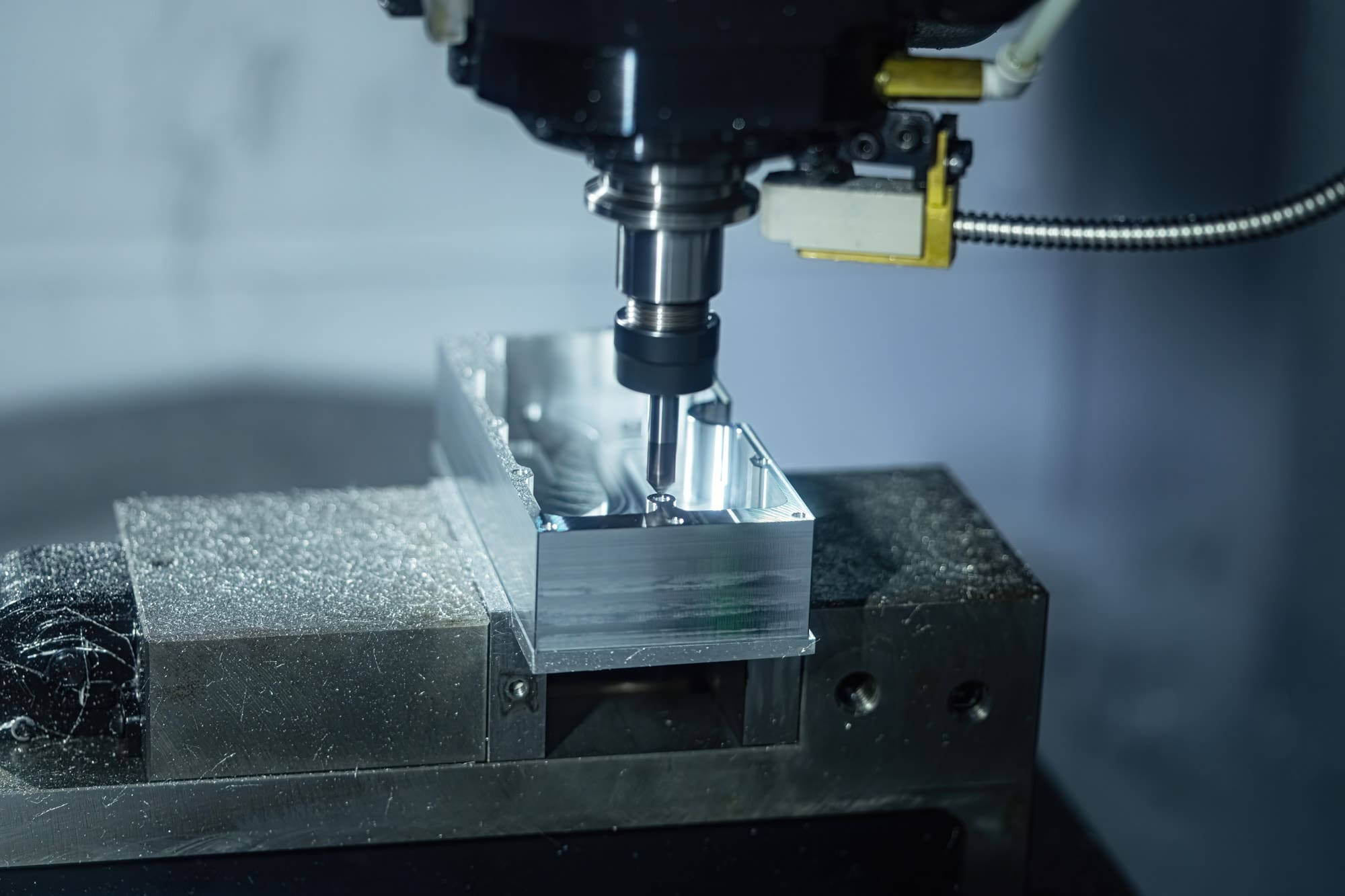 A CNC machine precisely mills a metallic block, surrounded by metal shavings