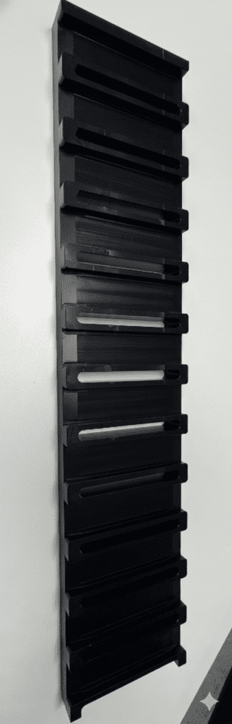 Vertical black rack with multiple slots for organizing items, mounted on a wall. Ideal for efficient storage solutions in homes or offices.